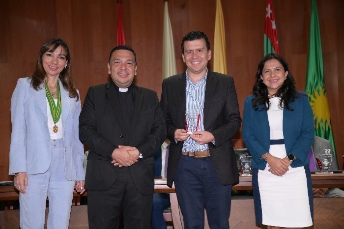 Docentes UPB Bucaramanga posando para una fotografía. Una persona tiene un reconocimiento en sus manos. 