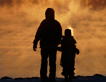 Siluetas de padre de familia con niño caminando hacia el horizonte