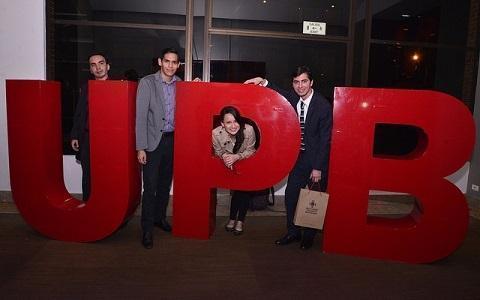 Egresados posando para una foto junto a las letras UPB