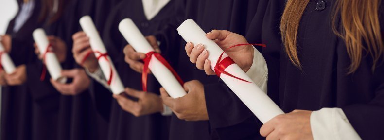 Estudiantes con toga de graduación sosteniendo diploma enrollado