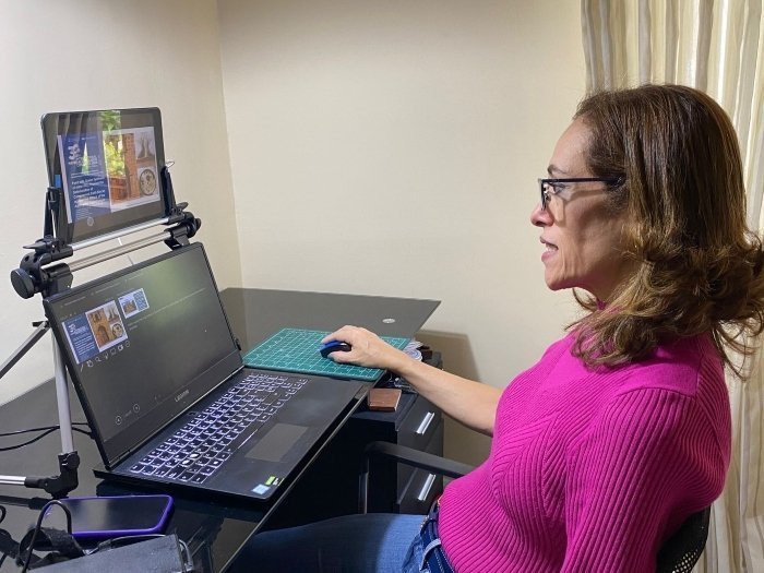 Docente mujer sentada frente a un computador haciendo la presentación de un proyecto