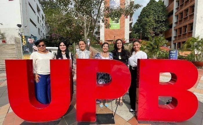 Personas posando para una fotografía en las letras grandes de la UPB